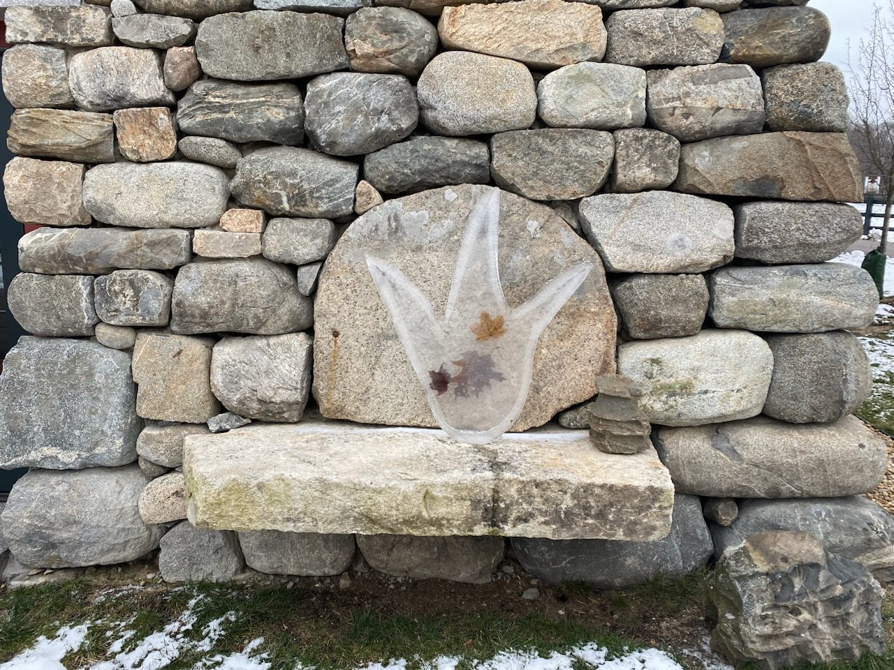 Stone wall with ice sculpture and leaves.